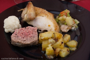 primo piano di pollo con il ripieno e guarnizioni di patate e verdure su piatto nero