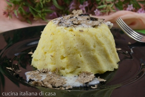 spuma di patate a forma di sformato su piatto nero con scaglie di tartufo nero e crema di tartufo